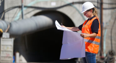 Environmental engineering consultant reviewing technical plans at infrastructure site in Italy, supporting permitting, remediation and sustainability projects